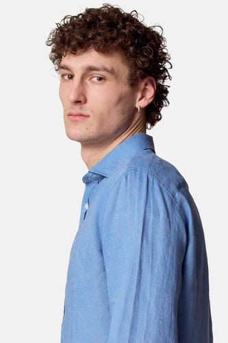 Man in blauw linnen overhemd, zijwaarts kijkend.