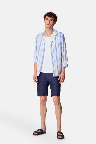 Chemise bleue à manches longues de Le Fabuleux Marcel de Bruxelles, à rayures bleues et blanches, portée sur un T-shirt blanc.