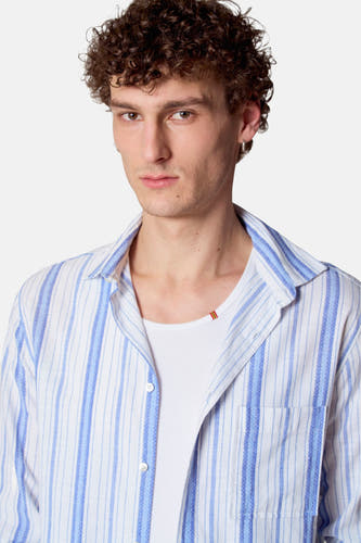 Chemise bleue à rayures à manches longues de Le Fabuleux Marcel de Bruxelles, portée sur une chemise blanche.