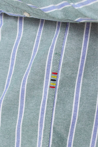 Chemise rayée verte à longues manches de Le Fabuleux Marcel de Bruxelles, gros plan sur les boutons et les points.