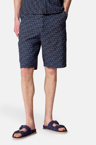 Man met blauwe bloemenshort en blauwe sandalen.