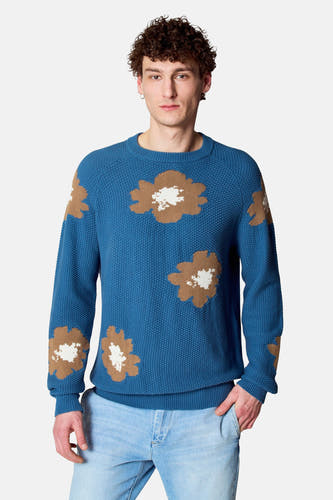 T-shirt bleu avec col rond de Le Fabuleux Marcel de Bruxelles, à imprimé floral et longues manches, associé à un jean bleu clair.