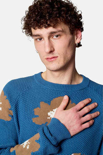 T-shirt bleu avec col rond de Le Fabuleux Marcel de Bruxelles, avec des motifs floraux bruns et main sur la poitrine.