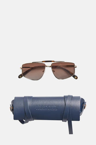 Lunettes de soleil dorées de Le Fabuleux Marcel de Bruxelles, avec des verres marrons et un étui bleu.