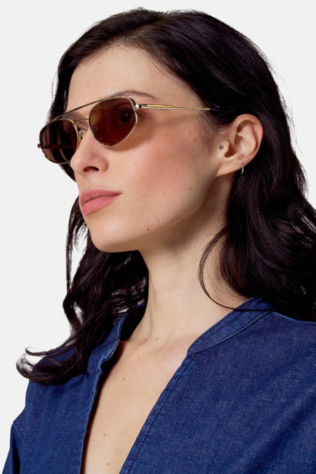 Chapeau de soleil doré du Le Fabuleux Marcel de Bruxelles, porté par une femme avec un t-shirt denim bleu.