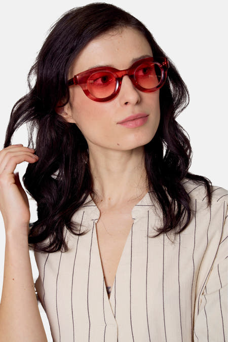 Lunettes de soleil roses de Le Fabuleux Marcel de Bruxelles, avec des verres ronds et un cadre transparent.