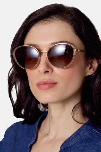 Lunettes de soleil beige de Le Fabuleux Marcel de Bruxelles, avec des verres marrons et un cadre doré, portées par une femme en une chemise en denim.