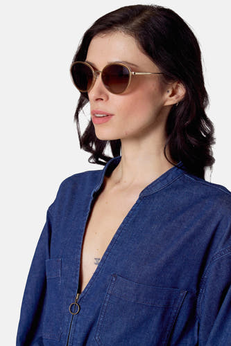 Lunettes de soleil beige de Le Fabuleux Marcel de Bruxelles, avec monture dorée et jumpsuit en denim.