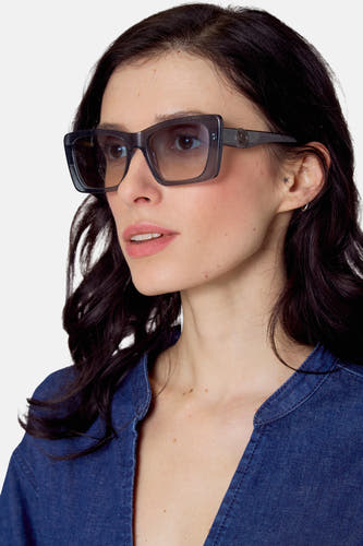 Lunettes de soleil bleues de Le Fabuleux Marcel de Bruxelles, portées avec une blouse en denim et des subtiles boucles d'oreilles.