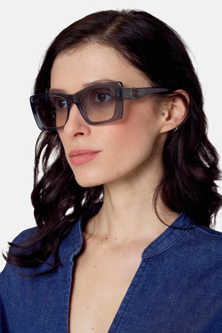 Lunettes de soleil bleues de Le Fabuleux Marcel de Bruxelles, portées avec un t-shirt denim bleu et une petite étoile tatouée sur l'oreille.