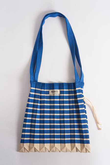 Sac à dos rayé bleu de Le Fabuleux Marcel de Bruxelles, avec fermeture éclair en corde blanche, sur un fond blanc.