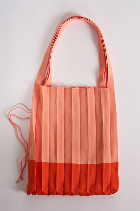 Manteau épaule orange de Le Fabuleux Marcel de Bruxelles, avec un design plissé et des accents orange en bas.