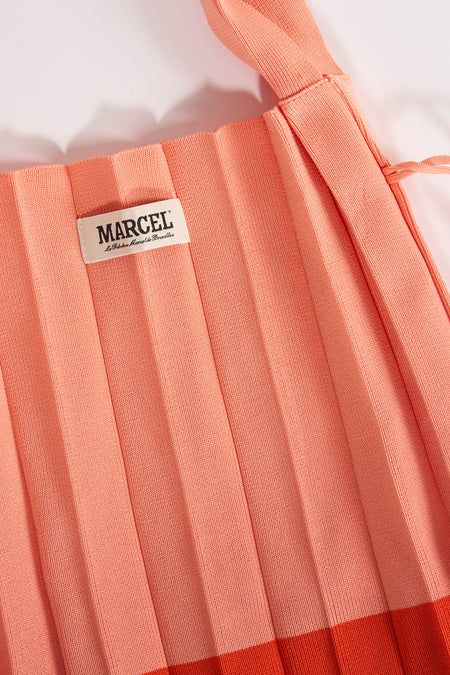 Manteau épaules orange de Le Fabuleux Marcel de Bruxelles, avec texture plissée et une étiquette.