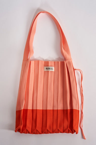 Manteau épaule d'Orange de Le Fabuleux Marcel de Bruxelles, avec un design plissé et une bandoulière assortie.