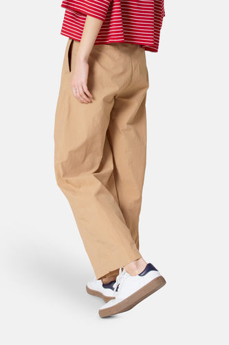 Persoon in khaki broek, gestreept rood-wit shirt en witte sneakers met bruine zool.