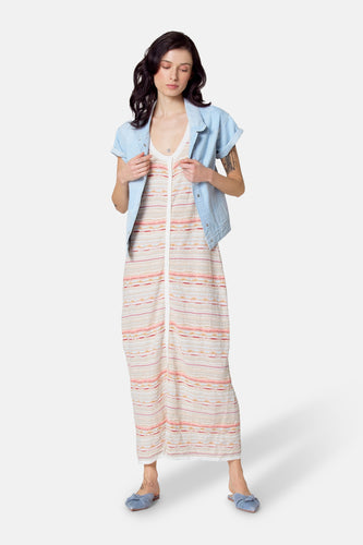 Vrouw in gestreepte jurk en denim jack, staand.