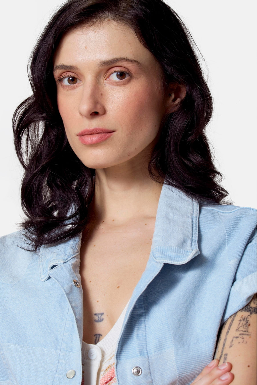 Lichtblauwe jeansjas van Le Fabuleux Marcel de Bruxelles, met zilverkleurige drukknopen en zichtbare tatoeages.
