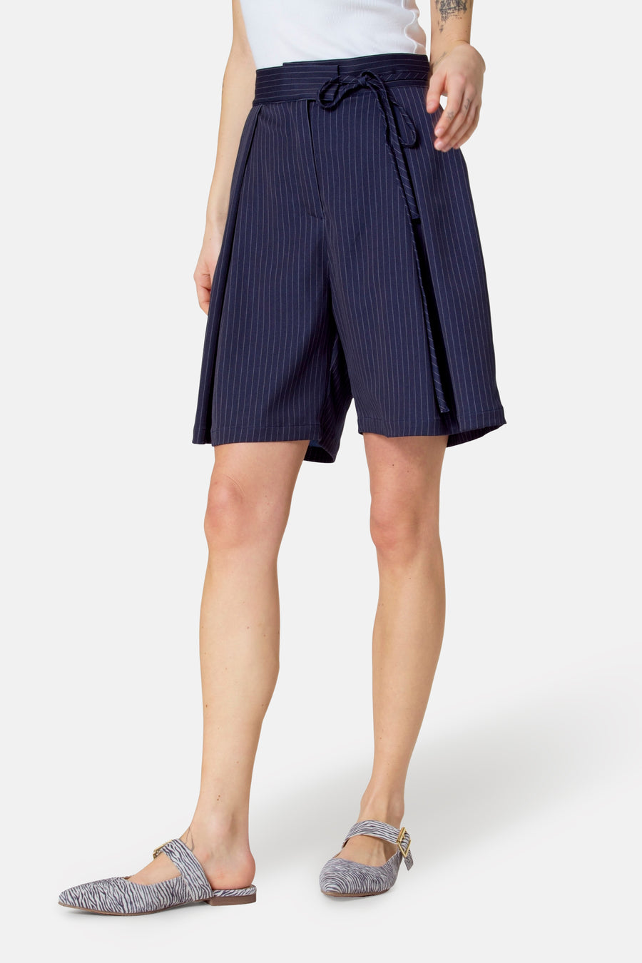 Vrouw in blauwe gestreepte broekrok en zebraprint schoenen.