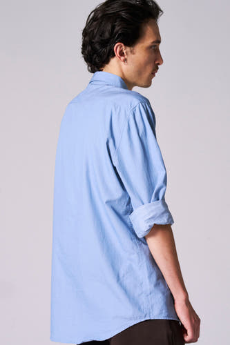 Chemise bleue à manches longues de Le Fabuleux Marcel de Bruxelles, avec des manches retroussées, vue de derrière.
