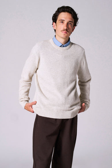 Pull beige avec col rond de Le Fabuleux Marcel de Bruxelles, avec des manches longues et un pantalon marron.