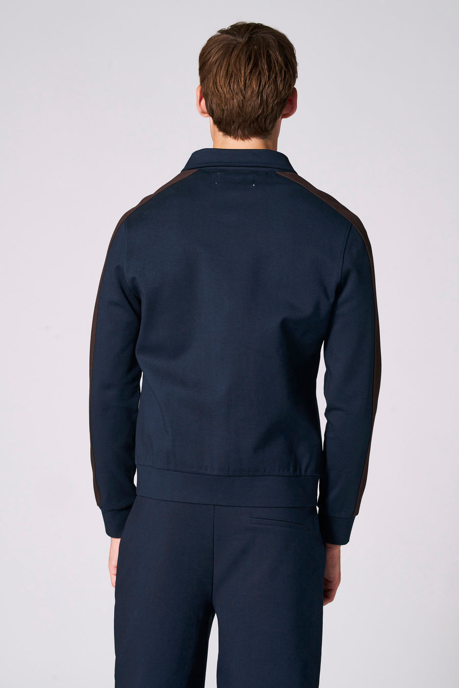 Achterkant van een man in een donkerblauw pak met bruine strepen.