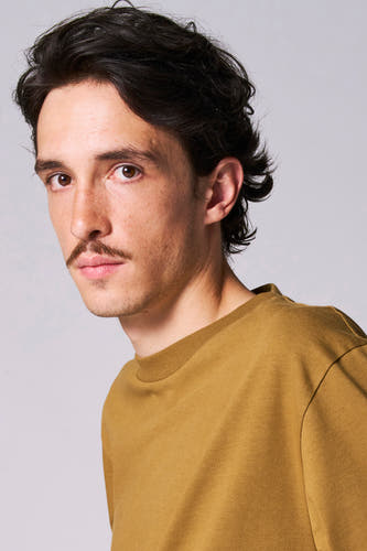 T-shirt beige à longues manches de Le Fabuleux Marcel de Bruxelles, porté par un homme barbu.