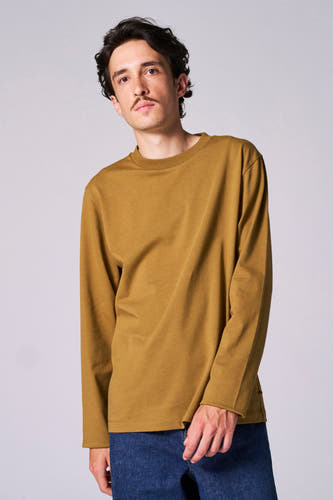 T-shirt beige à longues manches de Le Fabuleux Marcel de Bruxelles, porté avec un pantalon de travail bleu marine.