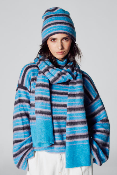 Manteau d'hiver multicolore de Le Fabuleux Marcel de Bruxelles, avec des rayures horizontales et un chapeau et une chemise coordonnés.