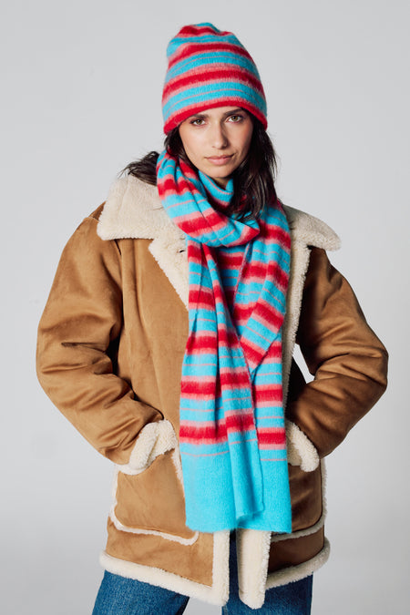 Écharpe d'hiver multicolore de Le Fabuleux Marcel de Bruxelles, à rayures, portée avec un chapeau et une veste coordonnés.