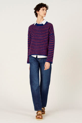 Pull multicolore à col rond de Le Fabuleux Marcel de Bruxelles, avec des rayures horizontales et combiné avec une chemise blanche et un jean.