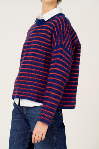 Pull multicolore à col rond de Le Fabuleux Marcel de Bruxelles, avec des rayures rouges, combiné avec une chemise blanche et un jean bleu.