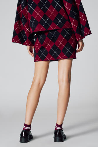 Short multicolored skirt from Le Fabuleux Marcel de Bruxelles, with a plaid pattern, combined with striped socks and black shoes.