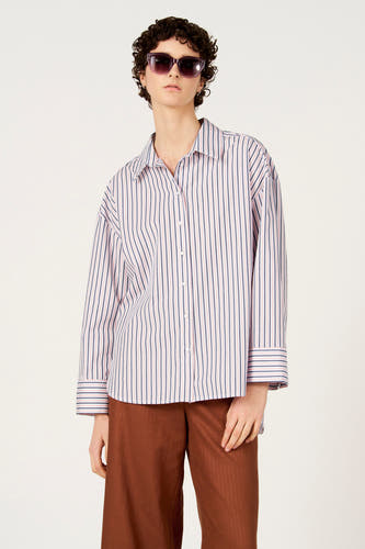 Chemise multicolore à manches longues de Le Fabuleux Marcel de Bruxelles, à motif rayé, portée avec un pantalon marron et des lunettes de soleil.
