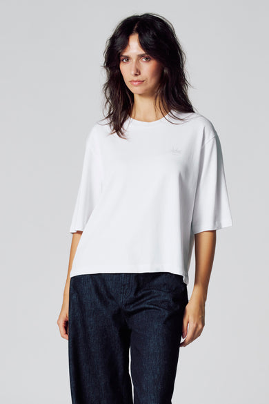 T-shirt blanc à manches courtes de Le Fabuleux Marcel de Bruxelles, porté avec des jeans bleus foncés.