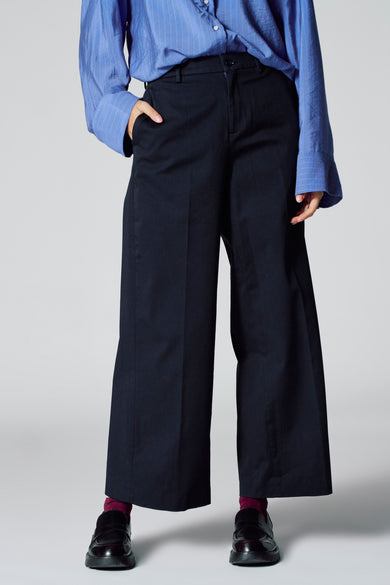 Jean bleu de Le Fabuleux Marcel de Bruxelles, avec des jambes larges et une coupe décontractée, associé à un chemisier rayé bleu.