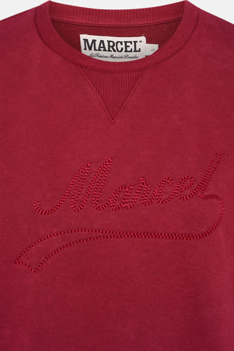 Gilet rouge de Le Fabuleux Marcel de Bruxelles, avec du texte brodé sur l'avant et un col rond.