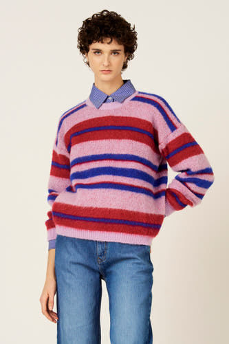 Pull multicolore de Le Fabuleux Marcel de Bruxelles, avec des rayures horizontales roses, rouges et bleues, porté sur une chemise à rayures bleues avec un jean.