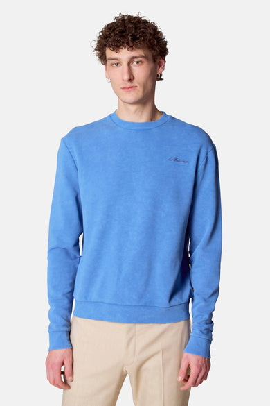 Pull bleu de Le Fabuleux Marcel de Bruxelles, avec des manches longues, vue arrière et associé à un pantalon beige.