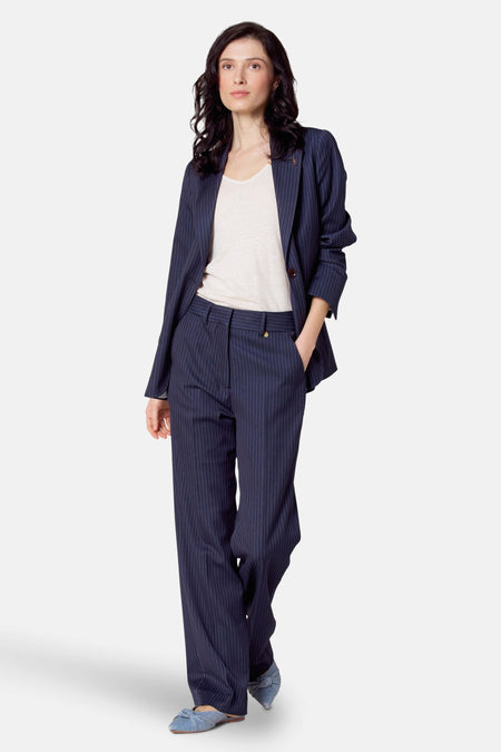 Blazer bleu de Le Fabuleux Marcel de Bruxelles, avec des rayures de craie, associé à un pantalon et et une chemise.