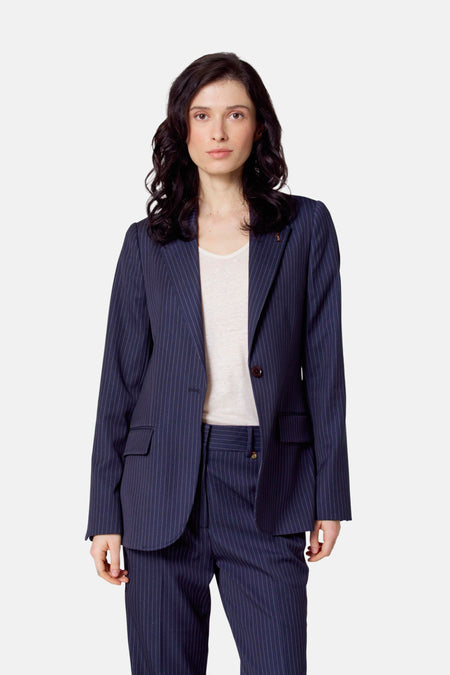Blazer bleu de Le Fabuleux Marcel de Bruxelles, avec une rayure blanche et un boutonnière en couleur or.