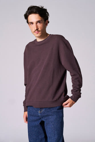 Pull marron avec col rond de Le Fabuleux Marcel de Bruxelles, porté avec des jeans bleus.