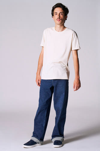 T-shirt blanc à manches courtes de Le Fabuleux Marcel de Bruxelles, porté avec des jeans et des baskets bleues.