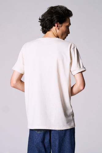 T-shirt blanc à manches courtes de Le Fabuleux Marcel de Bruxelles, vu par derrière, avec des manches retroussées et associé à un jean foncé.