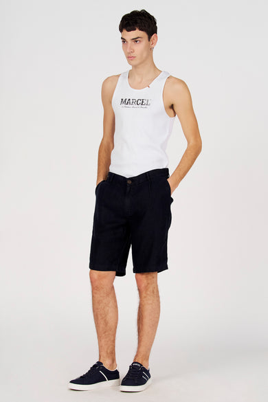 Bermuda bleu de Le Fabuleux Marcel de Bruxelles, porté avec un t-shirt blanc et des baskets bleues.