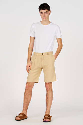 Bermuda beige de Le Fabuleux Marcel de Bruxelles, porté avec un t-shirt blanc et des sandales marron.