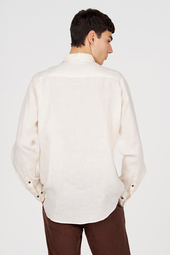 Chemise en lin blanc à manches longues de Le Fabuleux Marcel de Bruxelles, vue arrière avec boutons foncés et pantalon marron.