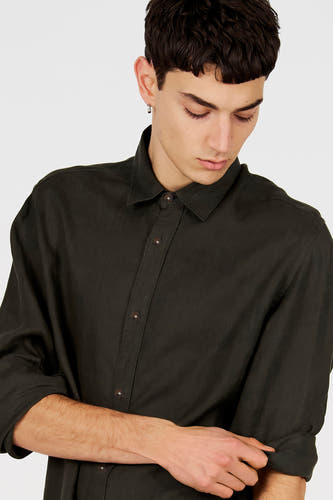 Chemise vert foncé de Le Fabuleux Marcel de Bruxelles avec texture visible, boutons marron et manches retroussées.