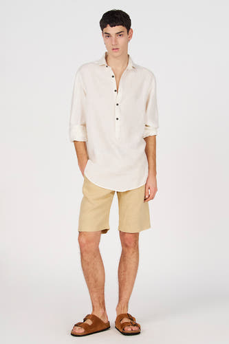 Chemise blanche en lin de Le Fabuleux Marcel de Bruxelles avec demi-patte de boutonnage, manches retroussées et boutons foncés.
