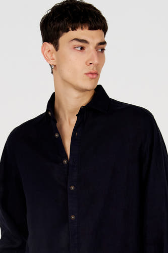 Chemise bleue de Le Fabuleux Marcel de Bruxelles, à manches longues, boutons marron et col ouvert, portée par un mannequin.