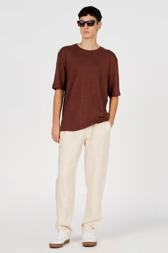 Chemise marron à manches courtes de Le Fabuleux Marcel de Bruxelles, à motif uni, portée avec un pantalon crème et des chaussures blanches.